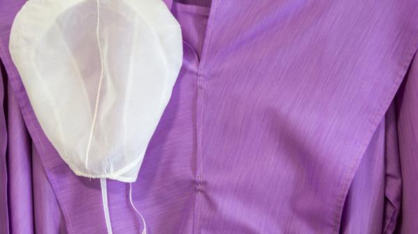 closeup of purple amish dress and white kapp
